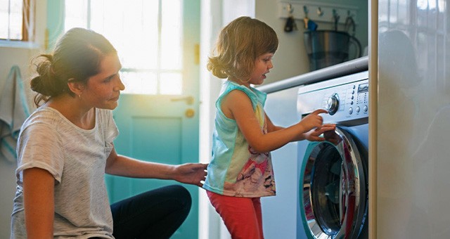 mother showing daughter how to program washing machine